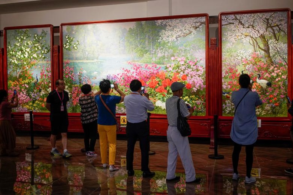 Khách tham quan đứng trước những tác phẩm nghệ thuật của các nghệ sĩ Triều Tiên trung tâm văn hóa Trung Quốc - Triều Tiên ở Đan Đông. Nhân viên ở đây cho biết mỗi bức vẽ của nghệ sĩ Triều Tiên được họ bán với giá khoảng 100.000 USD.