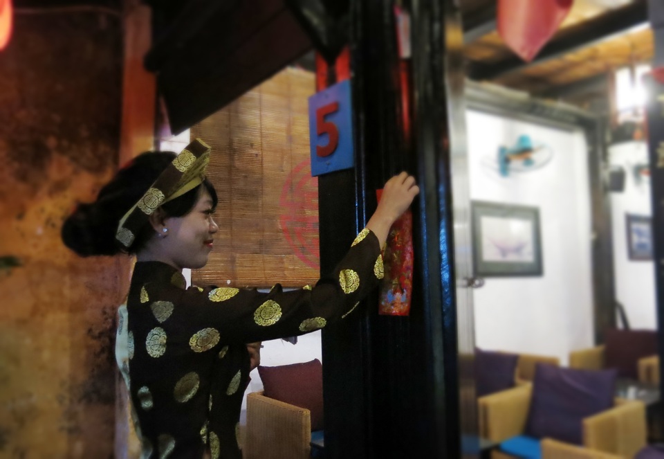 Thiếu nữ trong đoàn múa hát sắc bùa dán lộc may mắn cho nhà dân.