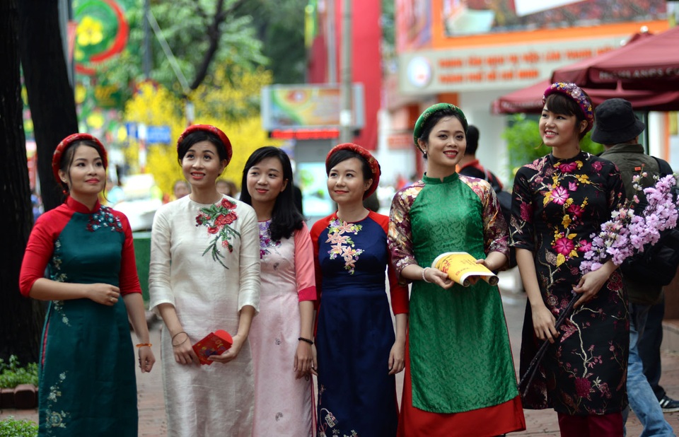 Nhóm thiếu nữ xúng xính với áo dài, khăn đội đầu và những cành hoa.