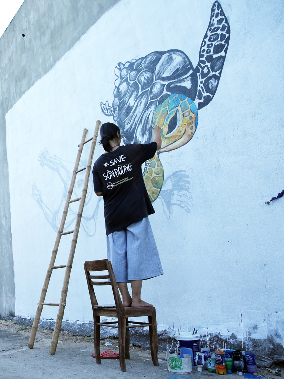 Một tình nguyện viên đến từ Hà Nội đang thực hiện bức tranh “Live together” trên bức tường nhà dân với thông điệp hướng về một thế giới hòa bình, nơi con người và động vật chung sống với nhau.