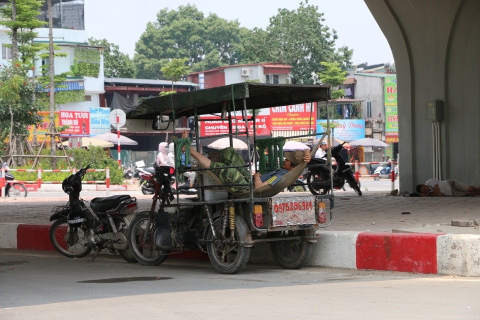 Nhọc nhằn những giấc ngủ trưa dưới nắng nóng của người lao động - 3 Chủ sở hữu những chiếc xe 3 bánh tận dụng thùng xe để mắc võng ngủ tránh cái nắng nóng gay gắt tại gầm cầu đường Cầu Giấy – Láng. Theo một người dân lao động cho biết: “Nắng nóng quá, buổi trưa tôi tranh thủ mang chiếu ra gầm cầu ngủ cho mát chứ ở chỗ trọ mái tôn hấp hơi xuống nóng như lửa đốt”.