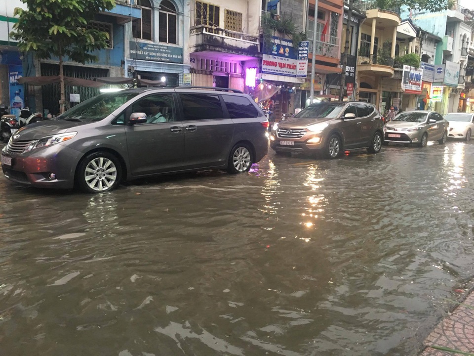 Đường Sài Gòn ngập nặng sau trận mưa không lớn - 2 Các nhân viên công ty thoát nước phải túc trực, bới rác từ các lỗ cống để nước rút.