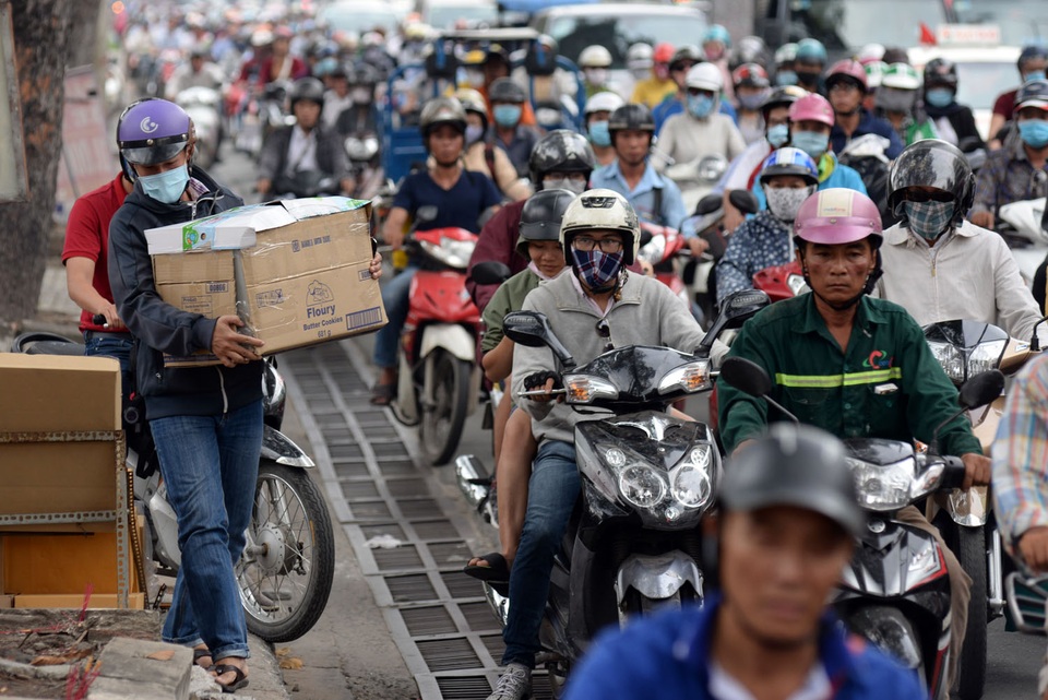 Một thanh niên phải ôm thùng hàng đi bộ trên vỉa hè để thoát khỏi cảnh kẹt xe.