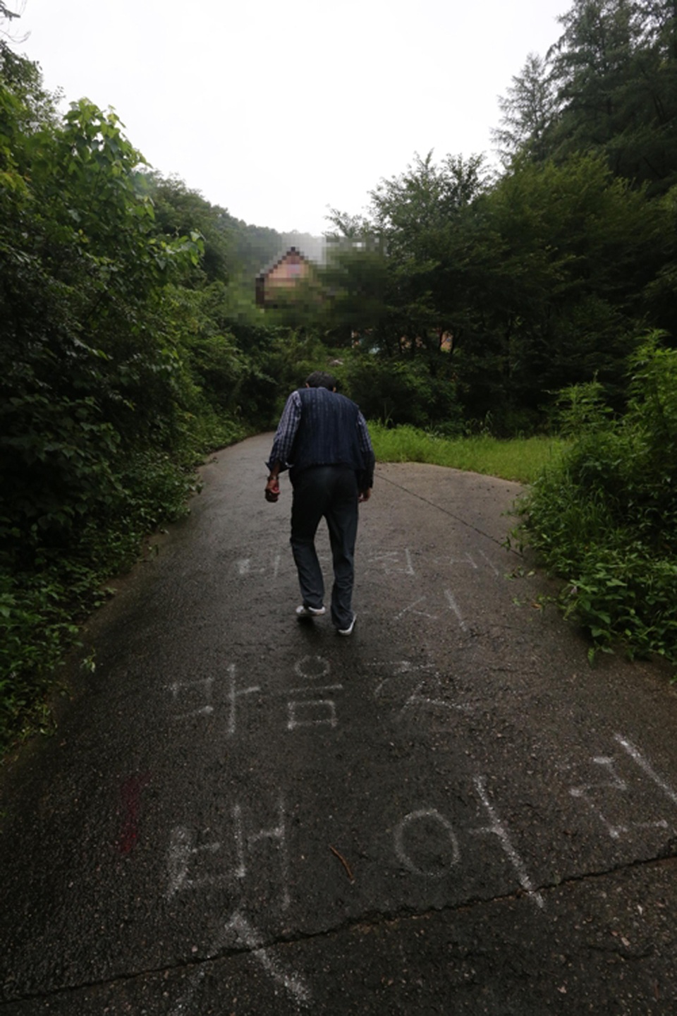 
Một cư dân trên con đường dẫn tới biệt thự với dòng chữ: Hãy cởi bỏ đồ của bạn thoải mái như ở nhà (Ảnh: Yonhap)
