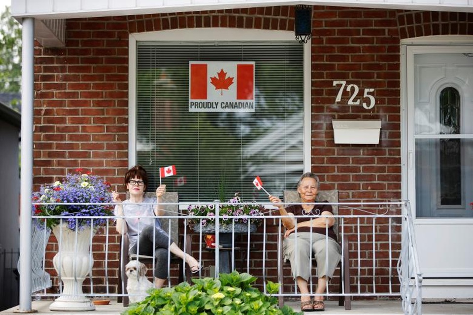 Những người phụ nữ vẫy cờ Canada khi xem sự kiện diễu hành nhân ngày Quốc khánh tại Toronto.