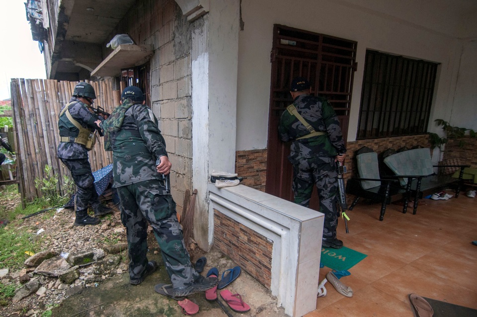Chiến sự ác liệt tại thành phố bị phiến quân bao vây ở Philippines - 2 Tham mưu trưởng quân đội Philippines Eduardo Ano cho biết liên minh các nhóm phiến quân thân tổ chức Nhà nước Hồi giáo tự xưng (IS) tiếp tục chiếm quyền kiểm soát ở khu vực trung tâm thành phố, tương đương 10% diện tích của Marawi. Trong ảnh: Một nhóm cảnh sát và binh lính quân đội lục soát từng ngôi nhà để truy lùng các tay súng phiến quân ở Marawi. (Ảnh: Reuters)