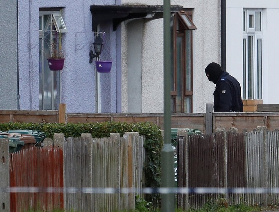 Một cảnh sát đeo mặt nạ tiến vào địa điểm tình nghi để khám xét và điều tra (Ảnh: Reuters)