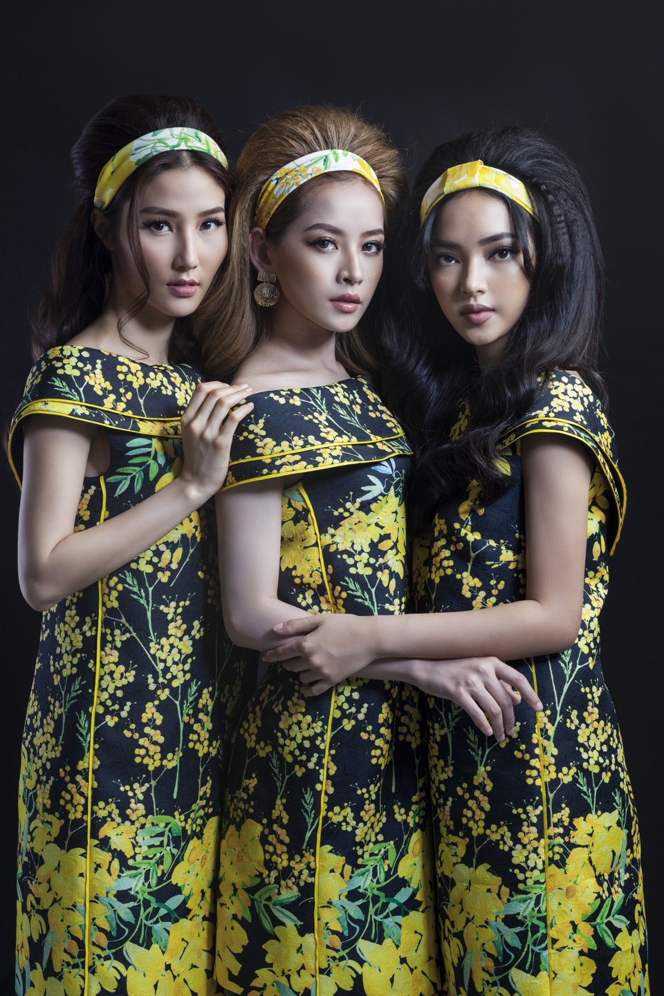 Cả ba đều diện thiết kế phom rộng với nền đen kết hợp hoạ tiết hoa tử đằng, hoa mimosa màu vàng rực rỡ. Kết hợp cùng trang phục là những chiếc băng đô cài tóc to bản đồng điệu màu sắc, hoạ tiết.