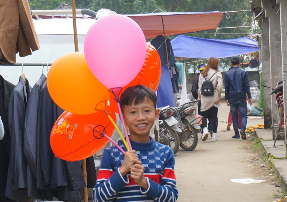 Trong khi đó, những đứa trẻ đến với phiên chợ Dinh cuối năm để bán bóng bay, kiếm tiền Tết phụ bố mẹ.