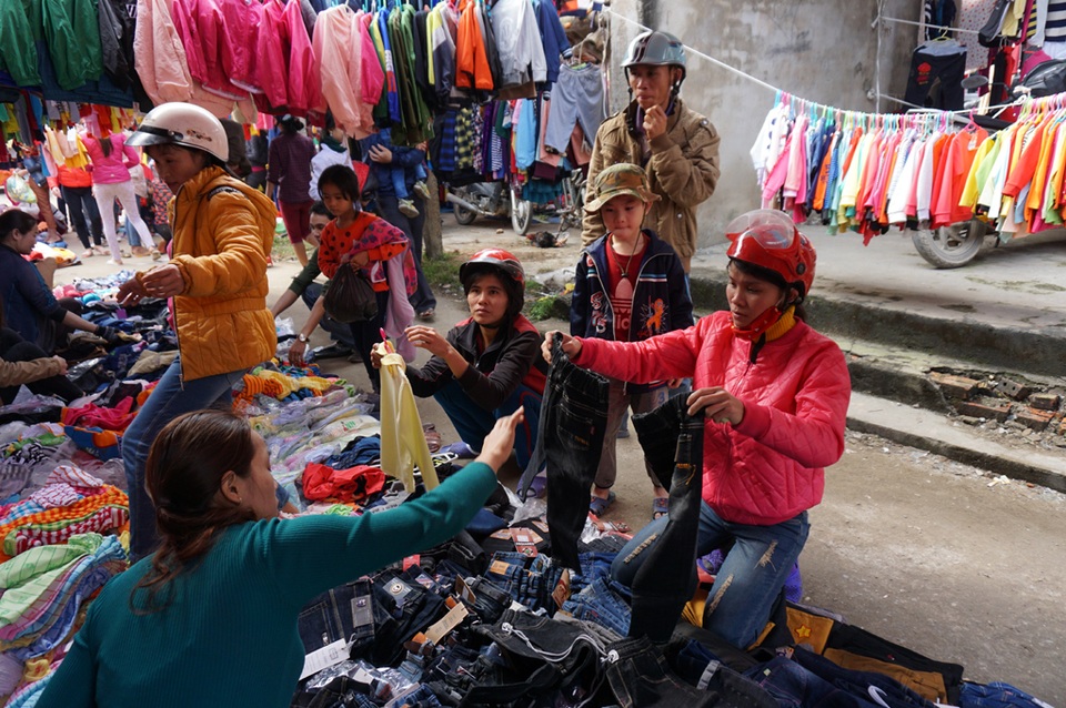 Các bà mẹ sắm cho con bộ quần áo mới. Chợ quê, chẳng cần quan tâm đến nguồn gốc, cứ miễn rẻ, đẹp là được. Người bán trải hàng lên tấm bạt, người mua mặc sức chọn. Tuy nhiên, năm nay, giá quần áo có tăng cao hơn mọi năm. Để sắm cho con 1 bộ quần áo diện Tết, các bà mẹ phải bỏ ra trên dưới 200 nghìn đồng.