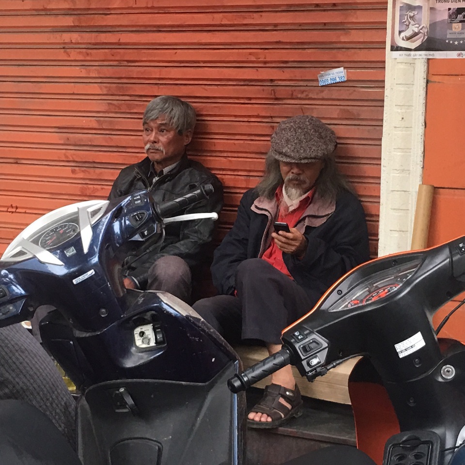 Con trai nhạc sỹ Văn Cao bàng hoàng trước vụ hoả hoạn - 2 Hoạ sỹ Văn Thao (đội mũ) cùng một người bạn thất thần theo dõi lực lượng chức năng tìm kiếm nguyên nhân vụ hoả hoạn. Thỉnh thoảng ông lại nhận được điện thoại từ người thân, bạn bè, đồng nghiệp gọi đến thăm hỏi. Ảnh: HTL.