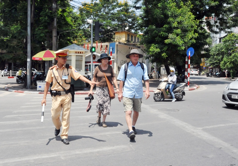 Cảnh sát giao thông mướt mồ hôi trong “chảo lửa” Hà Nội - 9
CSGT đưa 2 khách du lịch nước ngoài qua đường ở giao cắt Cửa Nam