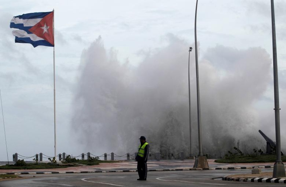 Cuba ngập trong biển nước sau siêu bão “quái vật” Irma - 1 Khi bắt đầu đổ bộ vào Cuba sáng ngày 9/9, siêu bão Irma mạnh ở cấp độ 5 - mức cao nhất trên bảng đo cấp độ bão Saffir-Simpson. Trước đó, cơn bão này đã càn quét một loạt các đảo ở Caribe, khiến ít nhất 28 người thiệt mạng và tàn phá nặng nề những nơi nó đi qua. Trong ảnh: Một sĩ quan cảnh sát đứng trên đường El Malecon ven biển cạnh con sóng cao bằng cột đèn tại thủ đô Havana khi bão Irma bắt đầu đổ bộ vào Cuba. (Ảnh: Reuters)