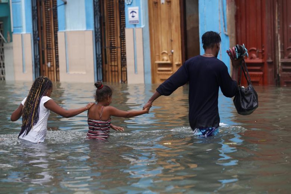 Cuba ngập trong biển nước sau siêu bão “quái vật” Irma - 3 Hiện chưa có con số chính thức về số người thiệt mạng hay bị thương do bão Irma tại Cuba. Chính phủ Cuba trước đó đã sơ tán hơn 1 triệu người dân tới nơi an toàn. Trong ảnh: Một người đàn ông dắt tay 2 em nhỏ đi qua một con đường ngập lụt ở Havana. (Ảnh: Reuters)