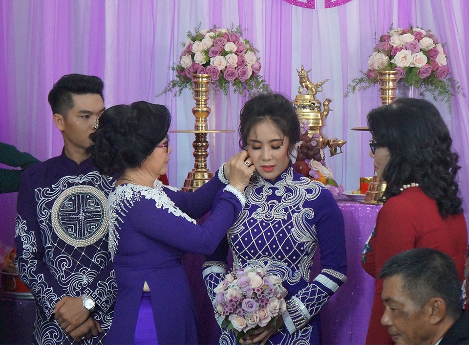 Mẹ cô dâu đeo bông tai cho con gái theo phong tục truyền thống trong hôn nhân.