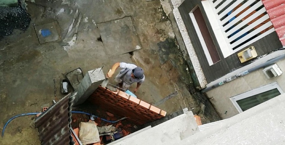 Đồng hồ nước đứt niêm chì, dân "thiệt đơn thiệt kép" - 1 Khi xây nhà, chị Hiển cho tường rào lùi vào trong để mở rộng khúc cua cho con hẻm nên đồng hồ nước nằm bên ngoài. Lúc này, hộp bảo vệ đồng hồ nước dưới chân anh thợ hồ (ảnh: nhân vật cung cấp)