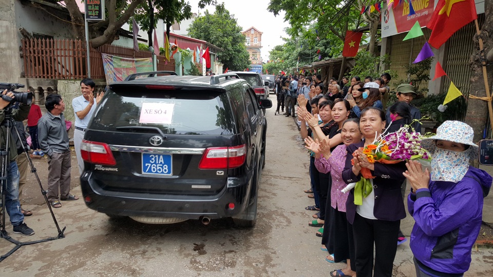 Người dân đứng hai bên đường chào đón đoàn công tác.
