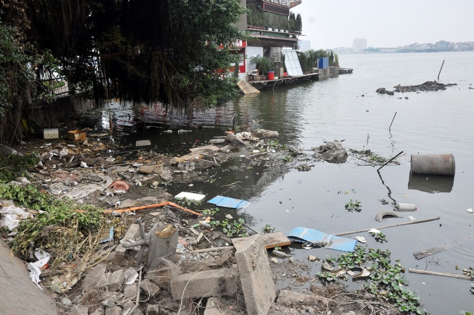 
Một nhà hàng ăn uống vừa tiến hành tháo dỡ cầu dẫn, sàn nổi, để lộ ra rác thải và vật liệu xây dựng ngổn ngang trên mặt nước.
