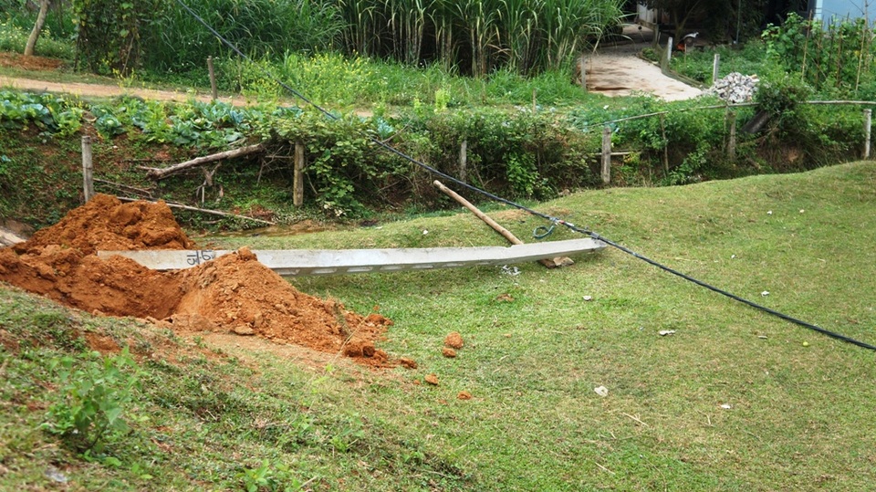 Một chiếc cột điện và dây bị xe kéo ngã xuống đất và làm mất điện trong xóm Hồng Nam 4 ngày qua.