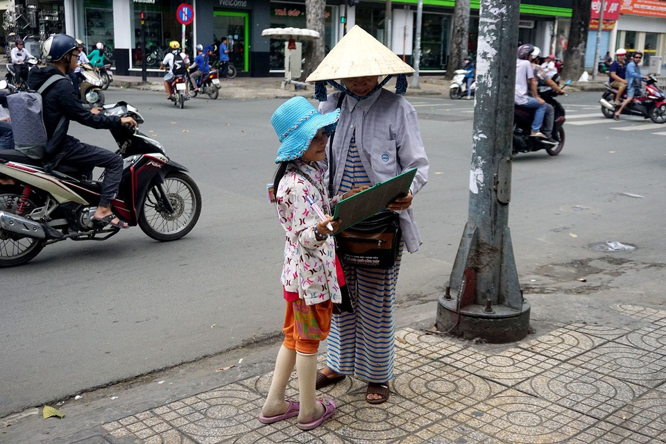 Nhân viên ngân hàng dành giờ nghỉ trưa dạy chữ cho bé bán vé số giữa Sài thành - 14 Thấy bà nội đến, cô bé chạy lại khoe những con chữ được thầy Tú mới dạy xong.