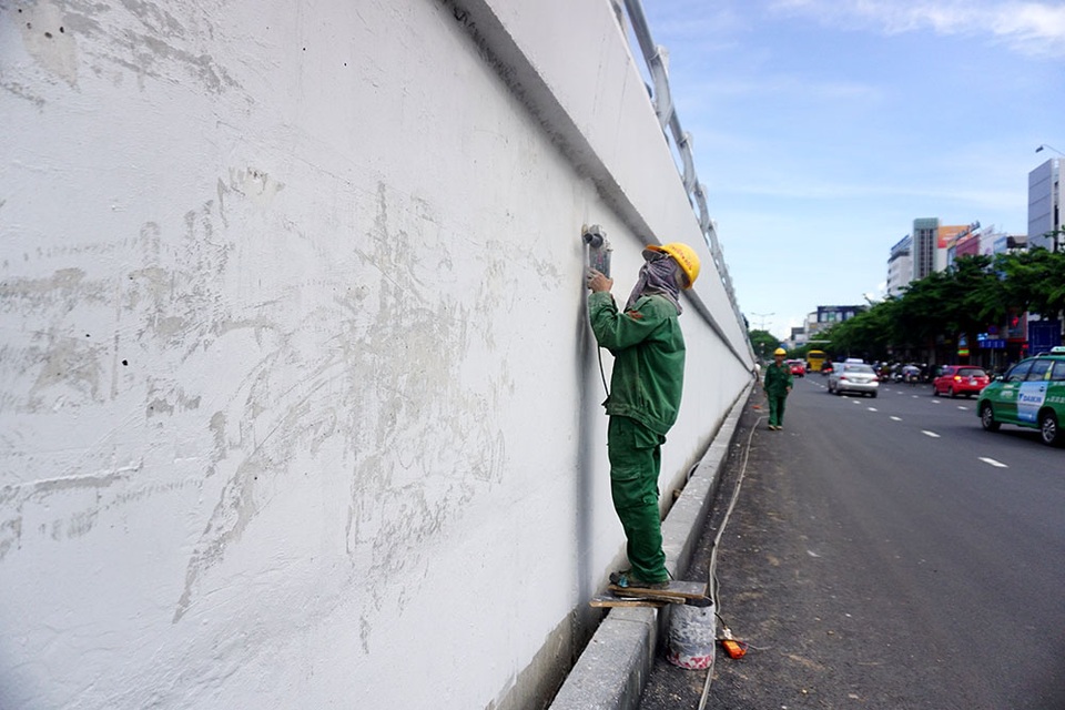 Các công nhân chà nhám các vết bẩn trên tường của cầu vượt.