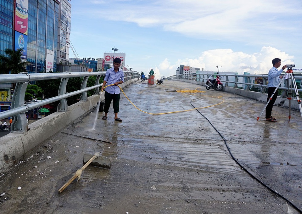 Các kỹ sư hỗ trợ công nhân dọn dẹp, phun nước lau chùi trên cầu vượt.