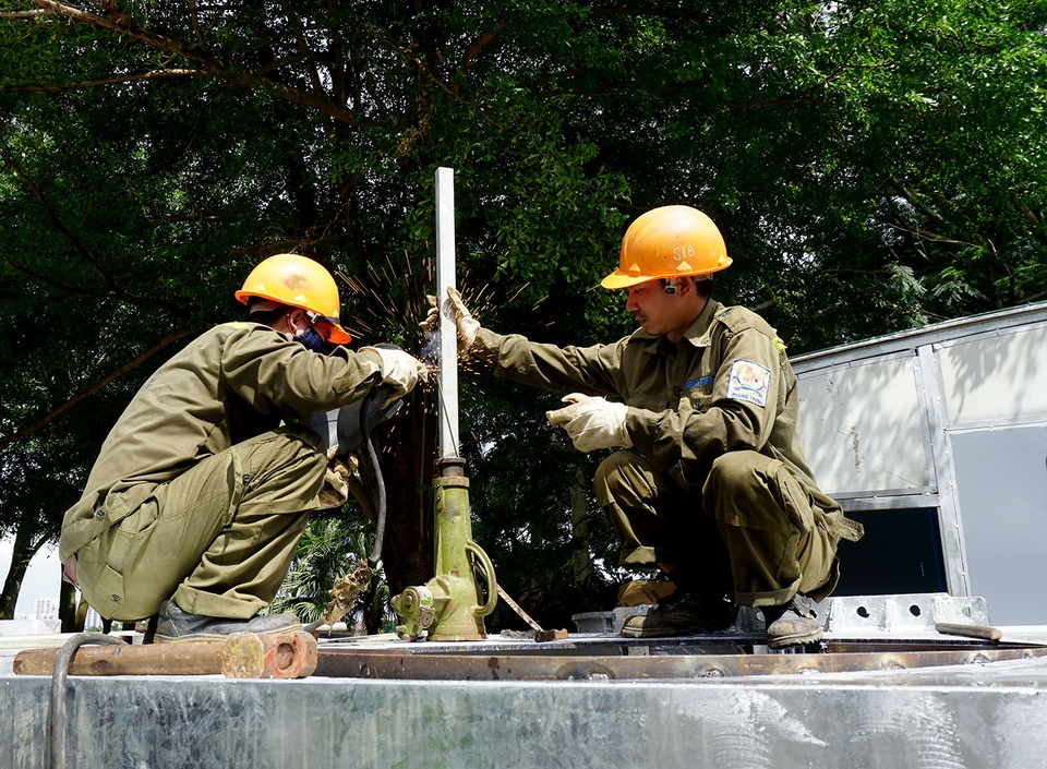 2 công nhân đang hàn thùng chứa nước đi kèm với đường ống dẫn nước của siêu máy bơm.
