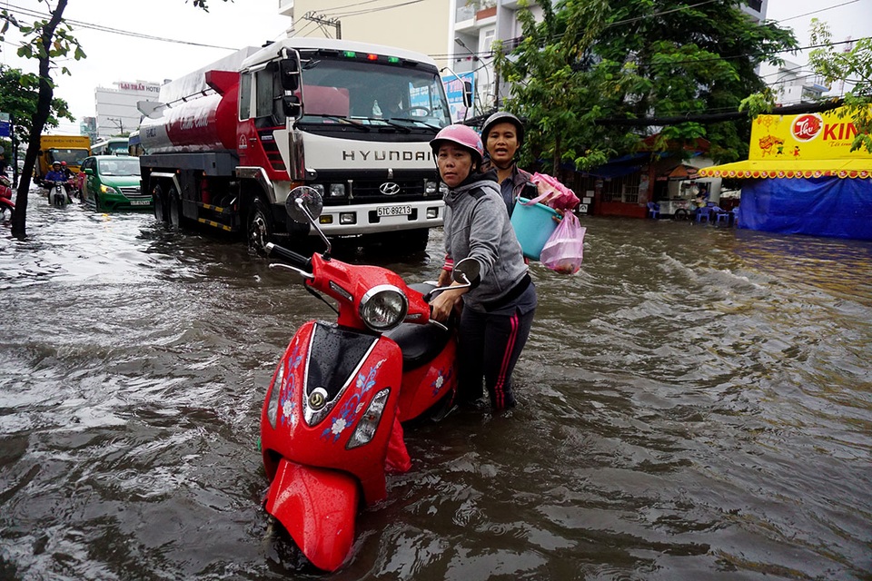 Đường ngập sâu, giao thông "tê liệt" sau cơn mưa lớn ở Sài Gòn - 12 2 người phụ nữ loay hoay trong dòng nước ngập sâu.