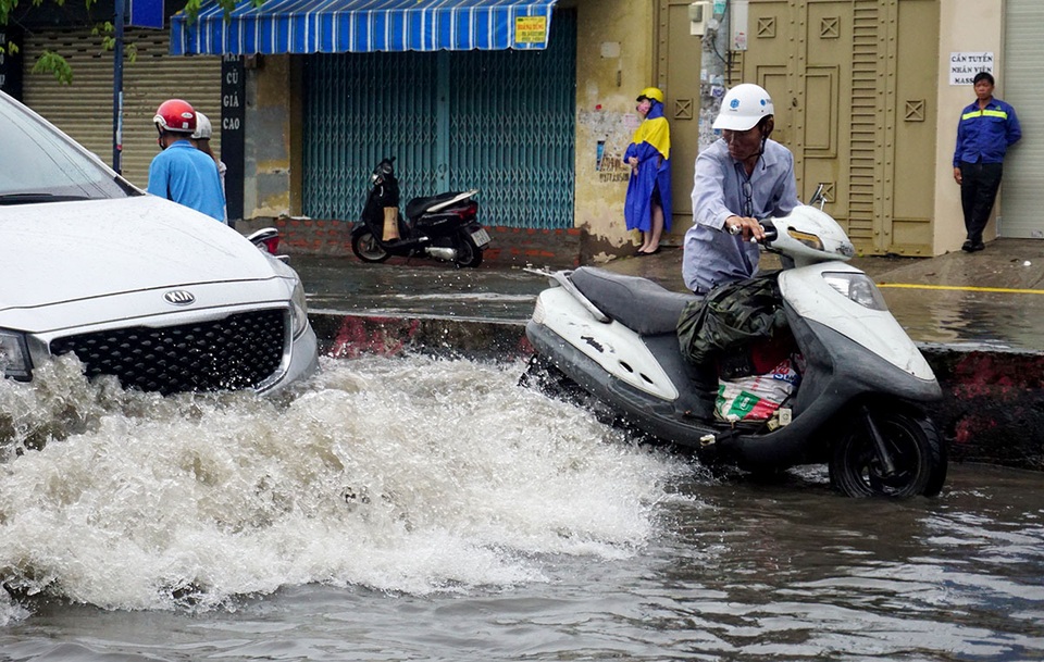 Đường ngập sâu, giao thông "tê liệt" sau cơn mưa lớn ở Sài Gòn - 5 Người đi xe máy khổ sở vì sóng của các ô tô đi bên cạnh.
