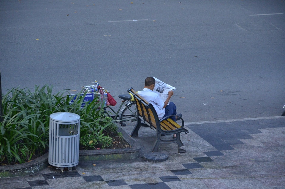 Một Sài Gòn không ồn ào, khác lạ trong ngày đầu năm mới - 4 Một người đàn ông thong thả ngồi đọc báo ở hồ Con Rùa