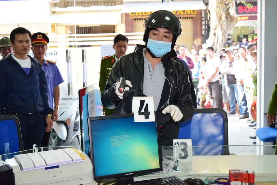 Thực nghiệm hiện trường vụ cướp ngân hàng ở Huế - 2
Đối tượng diễn lại cảnh xông vào ngân hàng đội mũ bảo hiểm, khẩu trang và chĩa súng giả vào nhân viên...