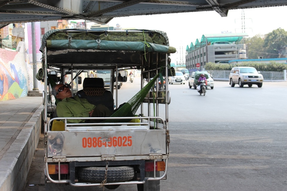 Một người lái xe ba gác tìm đến bóng mát dưới gầm cầu Long Biên và ngủ ngon lành trên chiếc võng quen thuộc.