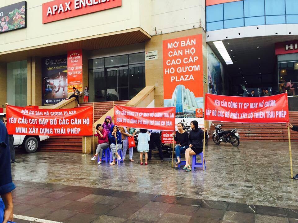 Cư dân đội mưa, giăng băng rôn trước toà nhà phản đối chủ đầu tư.