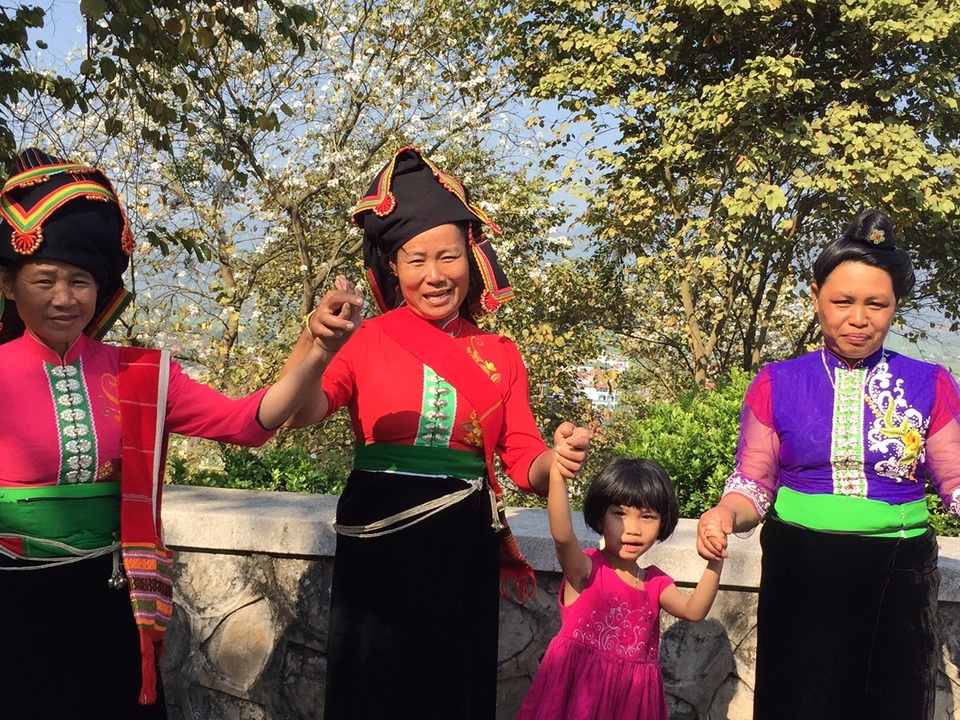 Bà con dân tộc Thái vui múa bên hoa ban trên đường lên Tượng đài Chiến thắng Điện Biên Phủ.