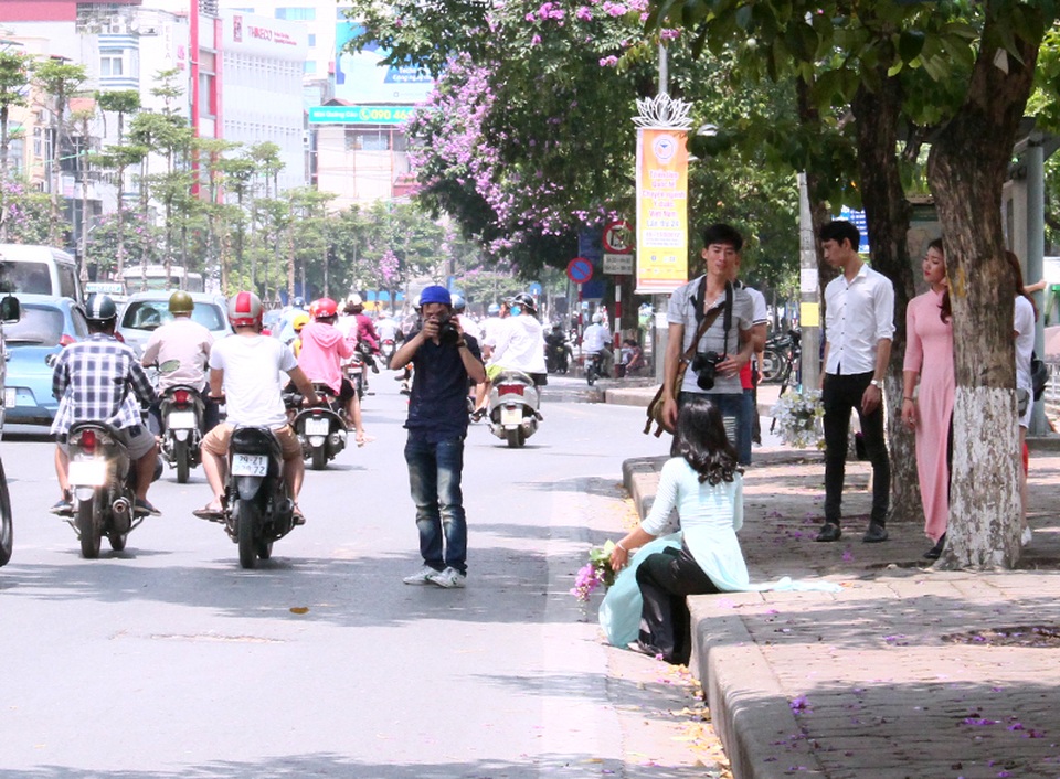Một nhóm nhiếp ảnh dành nhiều thời gian để tạo dáng chụp ảnh cho người mẫu với hoa bằng lăng.