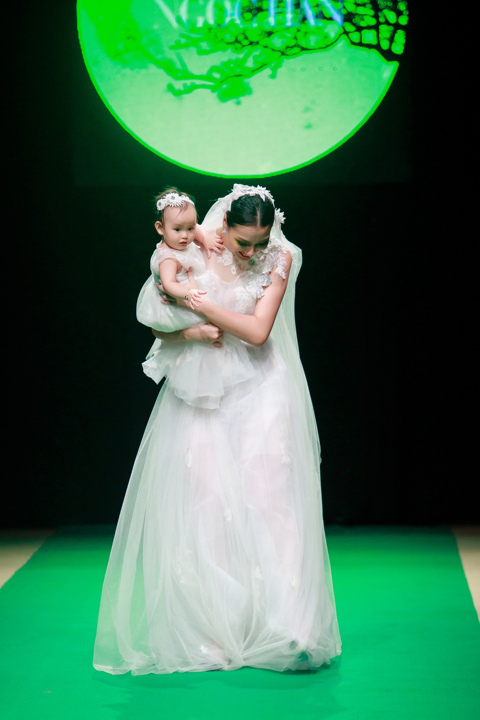 Dáng váy dài khiến Hồng Quế có lúc vấp nhưng với bản lĩnh và kinh nghiệm làm nghề, cô nhanh chóng tự tin bước tiếp. Bé Cherry từ nhỏ đã quen với ống kính và ánh đèn sân khấu nên không hề quấy khóc khi mẹ sải bước.