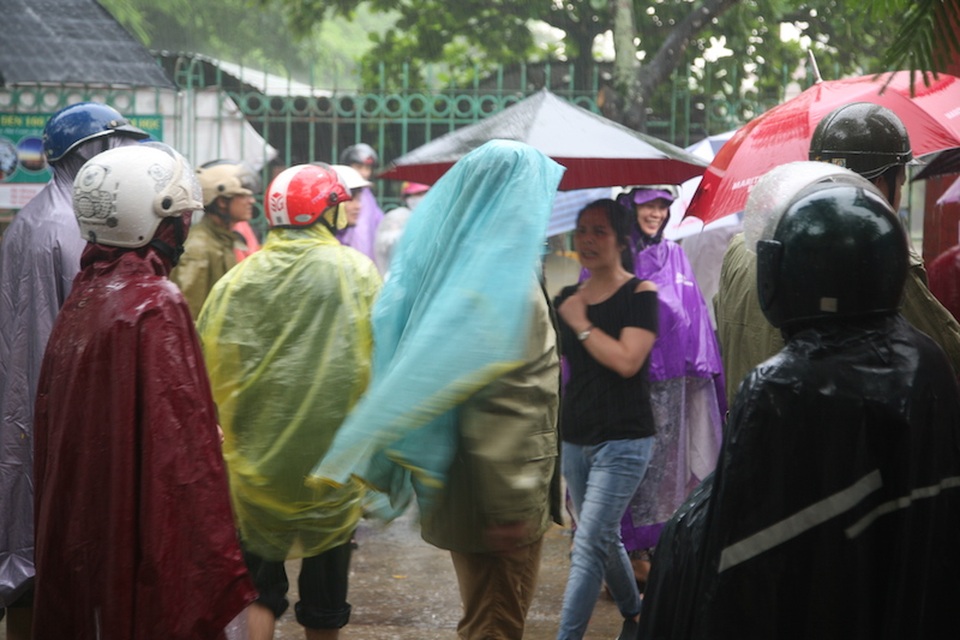 
Các phụ huynh đứng đội mưa đợi con ở ngay cổng trường
