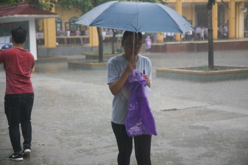 Một thí sinh mang theo ô ra khỏi điểm thi