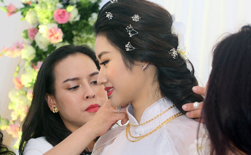 Thêm hình ảnh ngập tràn tình yêu của hoa hậu Thu Ngân trong ngày cưới - 5 Người thân giúp cô dâu Thu Ngân tháo bớt vòng vàng trên cổ