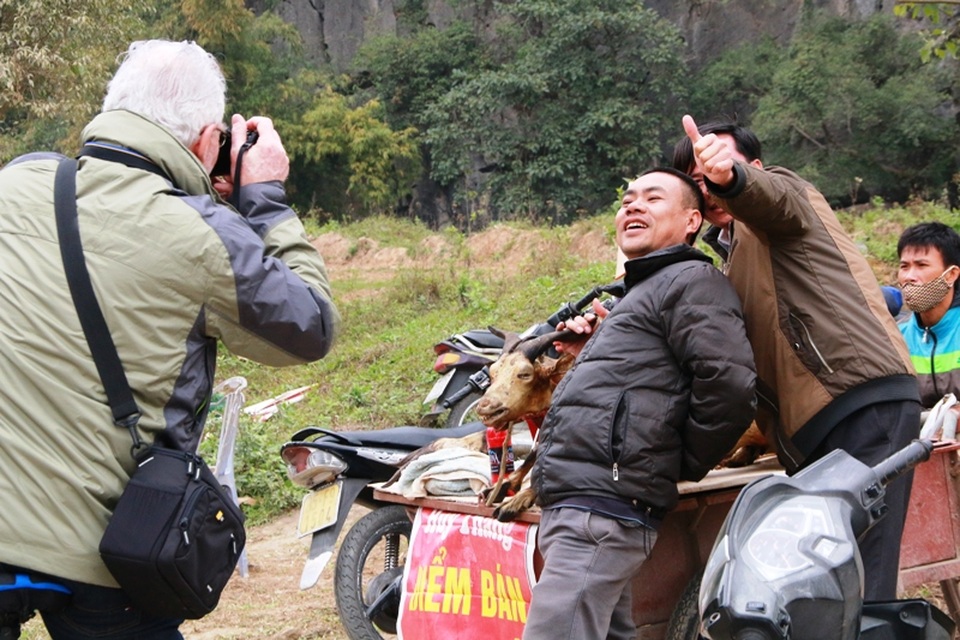 Người bán thịt dê tạo dáng cho du khách chụp ảnh bên con dê bán thịt của mình