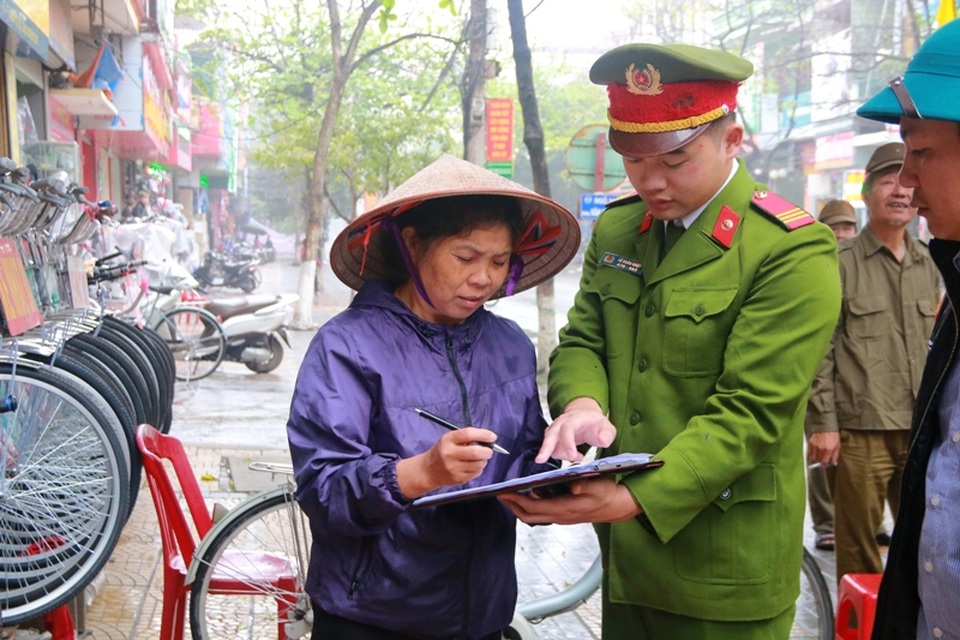 Lực lượng chức năng tuyên truyền, vận động người dân ký cam kết không lấn chiếm lòng đường, vỉa hè để buôn bán.