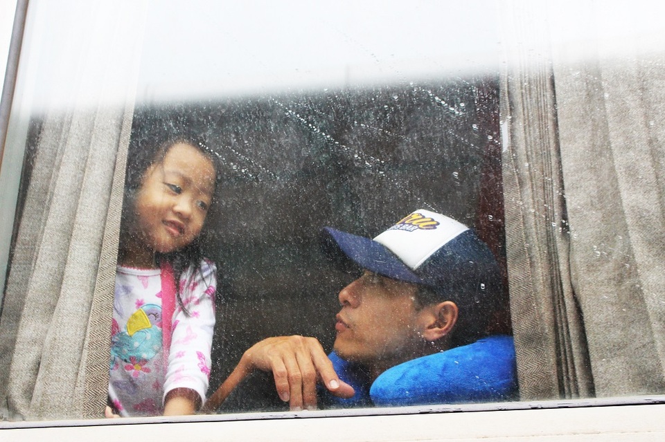 Một bé gái nhìn trời đang mưa từ ô cửa trên tàu hỏa. 