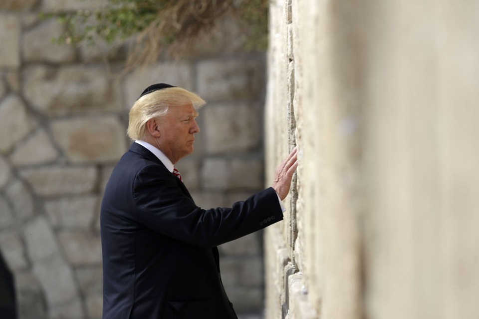 Vùng đất linh thiêng Jerusalem giữa điểm nóng Trung Đông - 1 Tổng thống Donald Trump ngày 6/12 tuyên bố công nhận Jerusalem là thủ đô của Israel và thông báo sẽ chuyển Đại sứ quán Mỹ từ Tel Aviv về vùng đất linh thiêng này. Động thái này của ông chủ Nhà Trắng đã làm dấy lên làn sóng phản ứng dữ dội từ cộng đồng quốc tế, đặc biệt là các nước Ả-rập. Trong ảnh: Tổng thống Trump đội mũ của người Do Thái chạm tay vào Bức tường Phía Tây ở Jerusalem khi tới thăm khu vực này ngày 22/5. (Ảnh: AP)