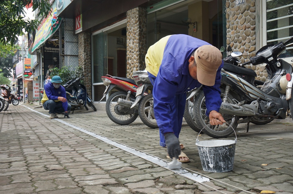Người dân phá tam cấp, trả vỉa hè trước “giờ G” - 1 Công nhân công ty CP Quản lý và phát triển hạ tầng đô thị Vinh kẻ vạch phân định ranh giới phần đường dành cho người đi bộ trên vỉa hè đường Nguyễn Văn Cừ (TP Vinh).