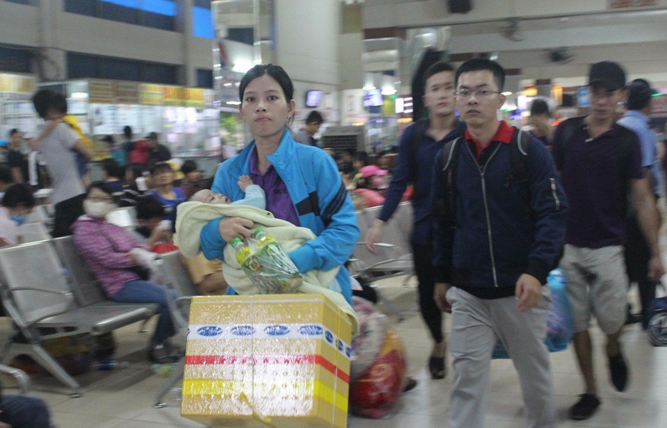 Một phụ nữ bế con ra bến xe để về quê…
