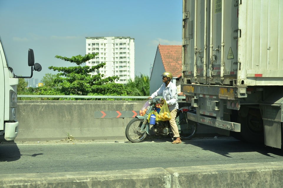 “Bò” suốt 2 tiếng chưa qua được cầu Phú Mỹ - 9 Một người dân chạy vào làn đường xe ô tô trên cầu Phú Mỹ để bán bánh mì cho tài xế