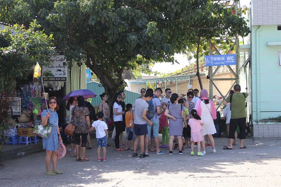 Nha Trang: Du lịch biển đảo nhộn nhịp du khách Trung Quốc - 2 Một người phụ nữ đang cầm cờ đợi khách và hướng dẫn đoàn khách Trung Quốc di chuyển