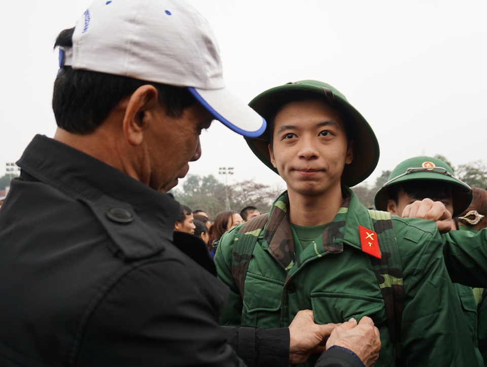 Cái nắm tay lưu luyến tiễn tân binh lên đường - 2 Người bố sửa sang lại quân phục cho con trai. Từ hôm nay, con trai của ông trở thành một người lính, nối tiếp bước chân cha thực hiện nghĩa vụ công dân đối với Tổ quốc.