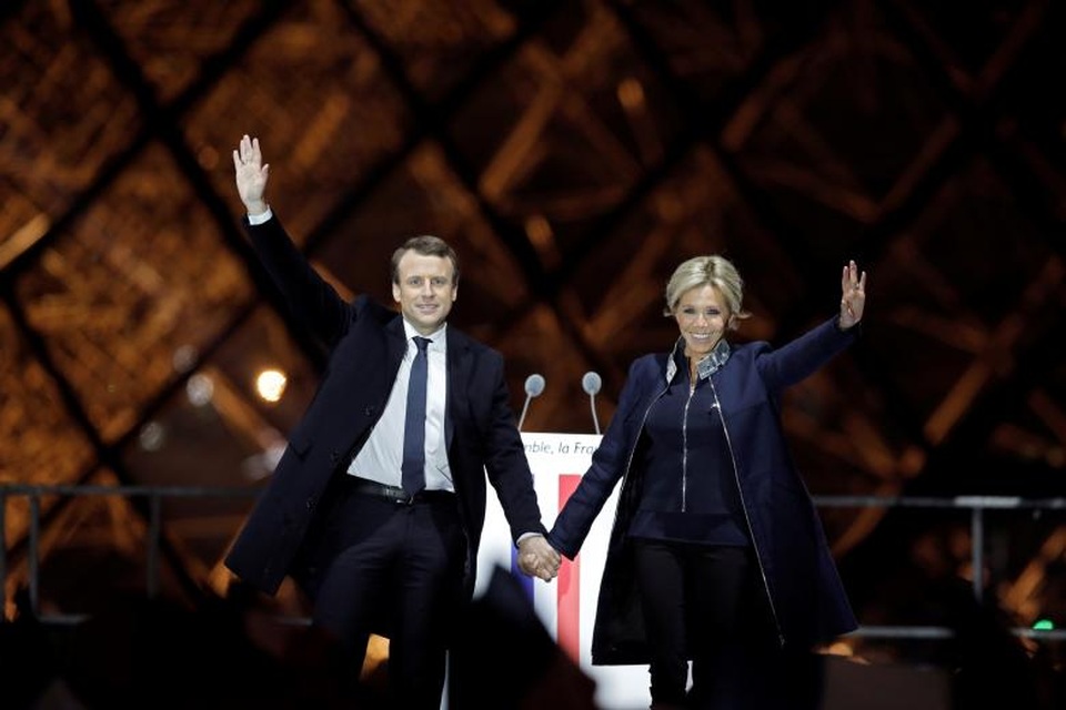 Người bạn đời hơn 25 tuổi nâng bước thành công cho Tổng thống đắc cử Pháp - 13 Ông Macron không ngần ngại công khai chuyện tình vốn được cho là “đũa lệch” của mình và luôn tự hào giới thiệu bà Brigitte với những người ủng hộ. Ngay cả những người con riêng của bà Brigitte cũng ủng hộ mối quan hệ của mẹ với cha dượng Macron. Người con gái thứ hai của bà Brigitte là Tiphaine Auziere cũng từng làm việc trong chiến dịch tranh cử của ông Macron và ca ngợi ông là một “người đàn ông thông minh” và “có tính cách đặc biệt”. Trong ảnh: Ông Macron nắm tay vợ trên sân khấu ăn mừng chiến thắng bầu cử hôm 7/5 bên ngoài bảo tàng Louvre tại Paris.