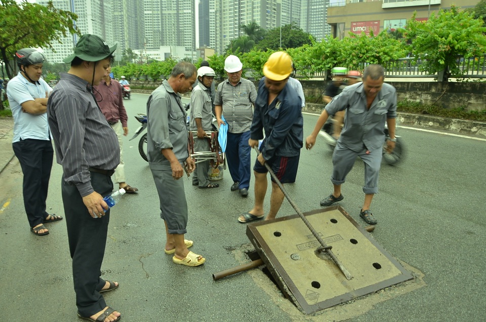 Đường Nguyễn Hữu Cảnh lại ngập nặng, chủ máy bơm “khủng” nói có phá hoại - 4 Các đơn vị liên quan tiến hành mở nắp cống để kiểm tra